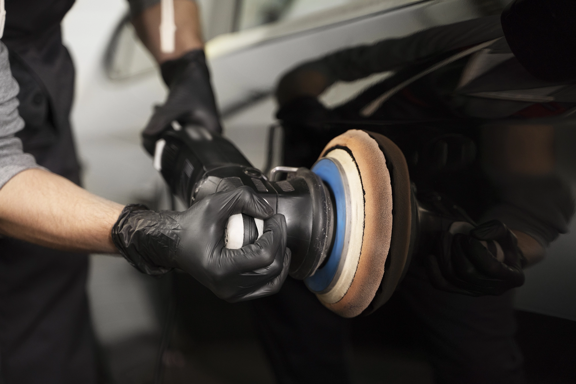 Fachmann poliert mit einer Poliermaschine die Fahrzeugtür vor dem Auftragen der Keramikversiegelung