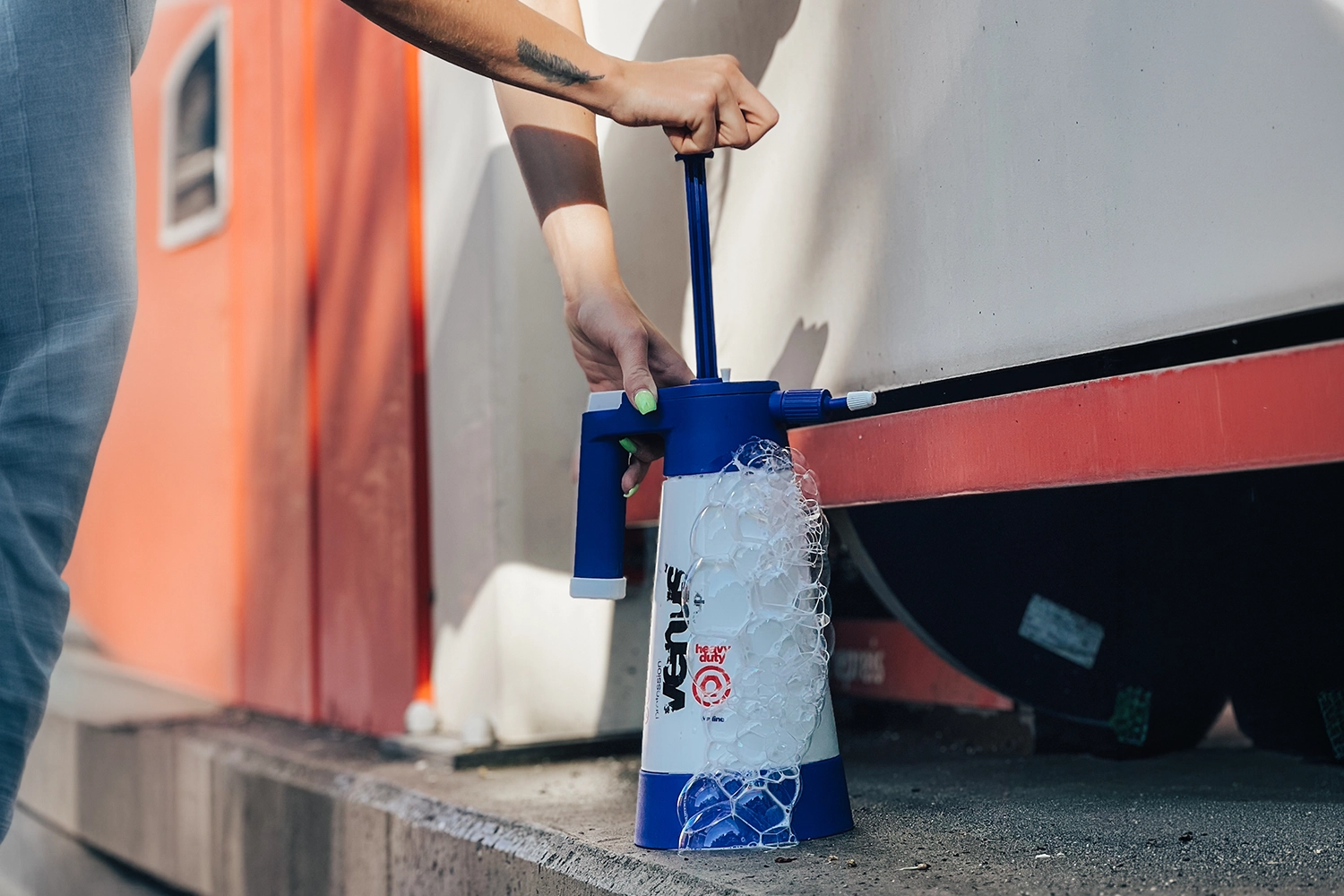 Auto waschen von Hand: dunkler Pkw wird mit Waschhandschuh und Autoshampoo gründlich eingeschäumt