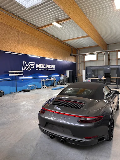 Halle von Autopflege Meilinger in Höchstädt: grauer Porsche 911 Cabrio vor der blauen Meilinger-Wand, beleuchtet für die Fahrzeugaufbereitung