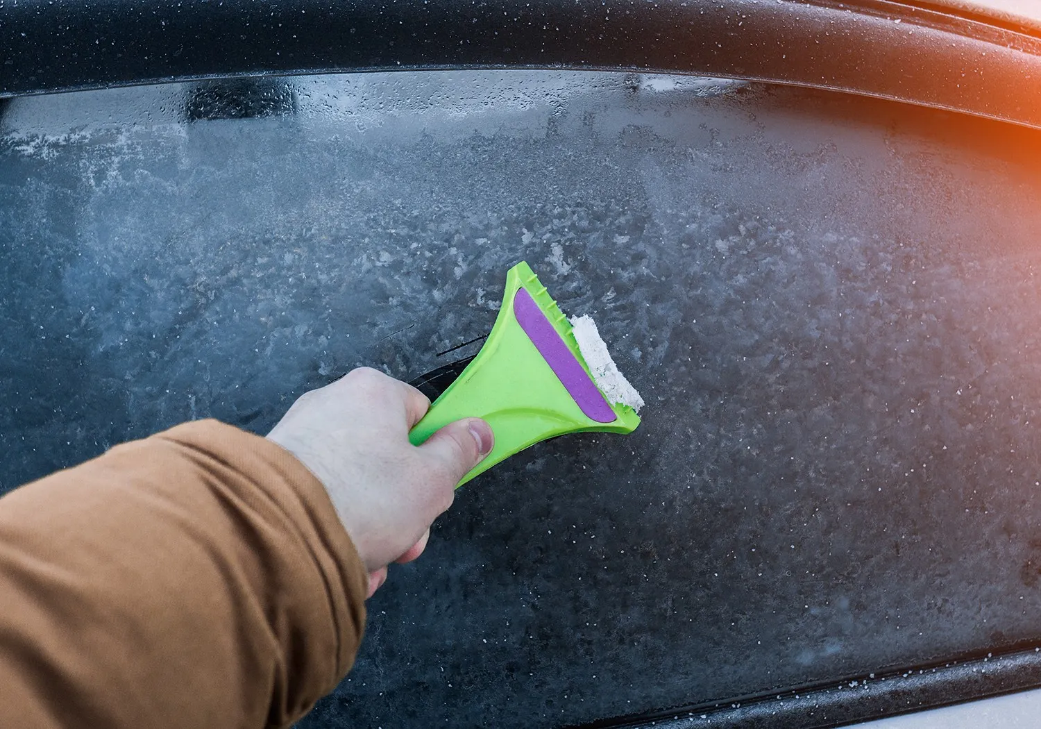 Scheibe enteisen mit einem Eiskratzer aus Kunststoff: vereiste Autoscheibe wird schonend freigekratzt